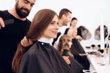 Several stylists make hairstyle for women of different ages in beauty salon.