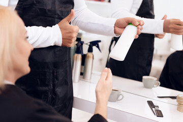 Female stylist show thumbs up to mature woman. Hairdresser recommend hair shampoo for woman. Mature pretty woman is doing hairdo in beauty salon.