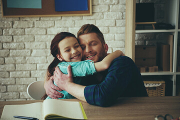 Red haired girl hugs happy father sitting at table
