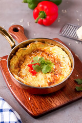 Egg Pizza Omelet with cheese, onions, and capsicum, garnished with cilantro and tomato cooked in a frying pan on a wooden board side view savory breakfast or brunch dish