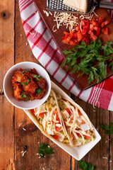 egg tortilla tacos with Indian potatoes, cheese, and tomato isolated on wooden table top view of fusion cuisine dish