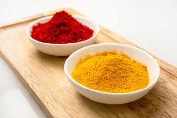 Aromatic spice paprika and turmeric powder in a white cup on a wooden background. Ground paprika and curcuma spices