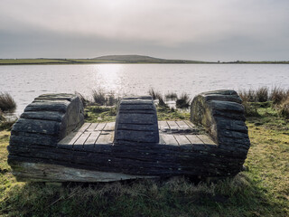 A rustic wooden bench by the side of a lake in Cornwall