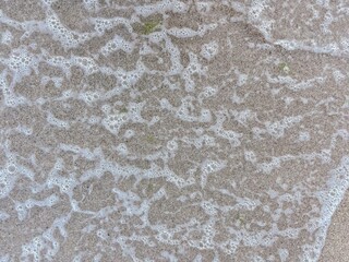 Ocean wave foam meeting smooth sandy beach in a relaxing seaside view