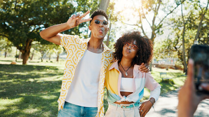 Fashion, cool and couple in park for photograph together for love, bonding or relationship in summer. Peace sign, social media influencer or men with women in nature for picture, vacation or holiday