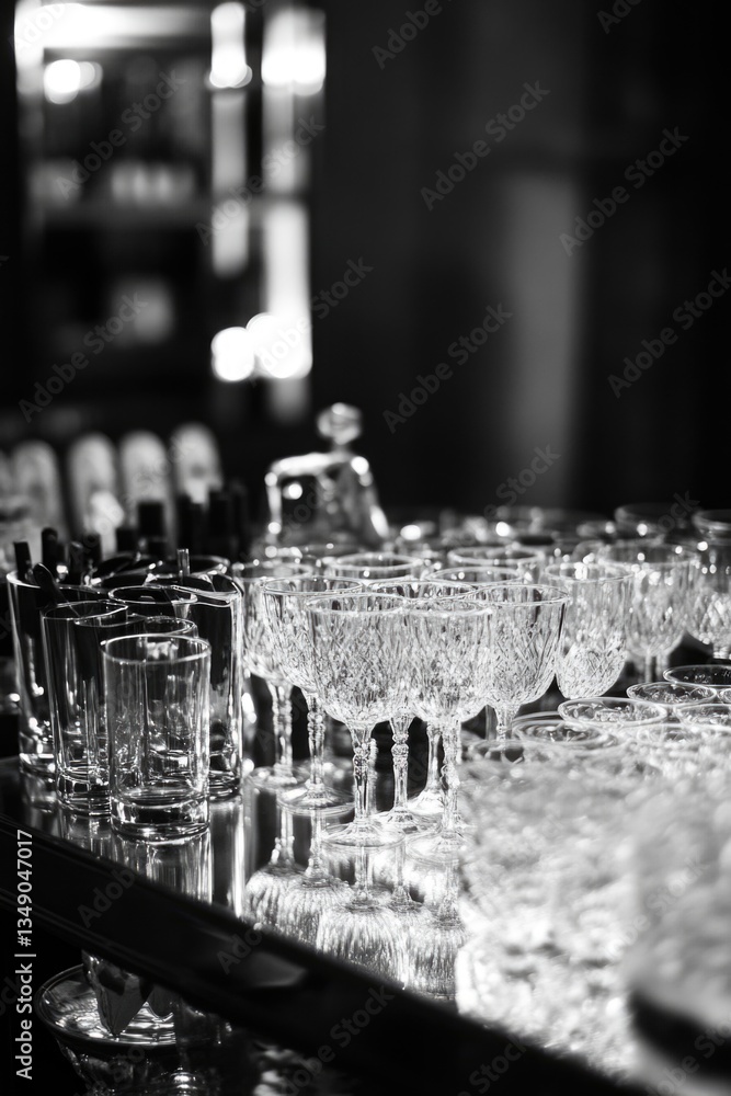 Poster a table full of glasses and bottles with a mirror behind them. scene is elegant and sophisticated