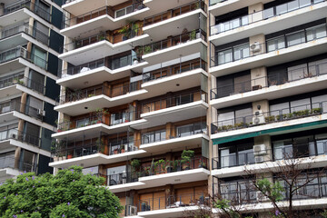 Apartment building for sale or rent. Facade of a multi-family home with balconies, gardens, and security nets