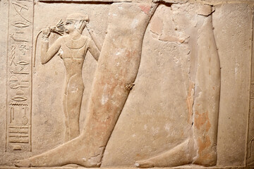 Mural from ancient Egyptian tomb in Saqqara showing the daughter of the vizier Kagemni at his feet,...