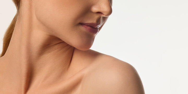 Cropped image of female face, neck and bare shoulders, young woman with glowing skin, emphasizing neck and jawline beauty. Concept of natural beauty, skin care, cosmetics, wellness, and healthy glow.