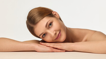 Portrait of beautiful young woman with healthy, smooth, clear skin gently posing against white studio background. Concept of beauty, skincare, dermatology, natural cosmetics, cosmetology