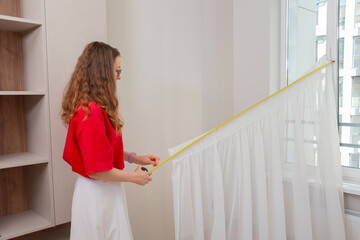 Designer checks the length of white tulle with a tape measure.