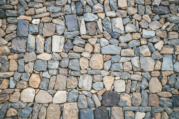 Rustic stone wall showcasing a mix of variously sized stones in natural hues. Ideal for background use