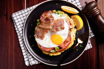 Fried Egg and Pork Waffles Food in a black plate on a wooden table