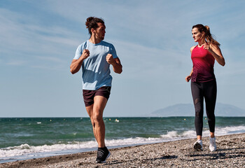Couple running on the beach, promoting healthy lifestyle and fitness together