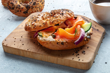 Lox bagel. A sandwich with smoked salmon and fresh vegetables on a wooden board, with coffee