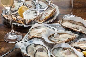 Fresh raw oysters on ice with lemon, on a wooden table. French restaurant, fine dining