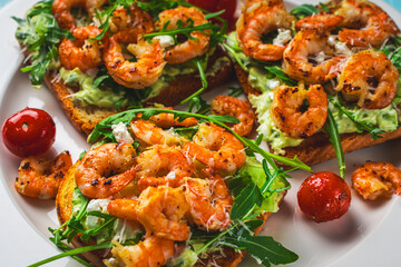 Toast with shrimp, avocado and arugula on a white plate with cherry tomatoes. Close-up. Healthy and Tasty Breakfast Concept