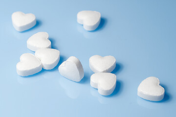 The medical concept of diseases of the human cardiovascular system. A heart-shaped tablet on a blue background. Selective focus..
