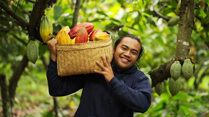 Portrait of a smiling young indonesian cacao farmer looking at the camera on a plantation with...