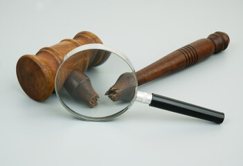 Injustice and court out of laws. Broken judge gavel under magnifying glass on gray background.