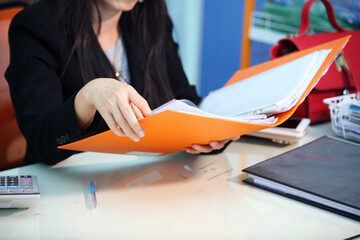Businesswoman Reviewing Documents in Office Setting with Files