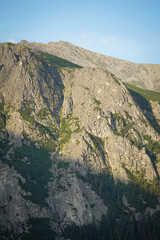 Mountain side cliffs and some green grass parts on it with bright blue sky background, High Tatra mountains, Slovakia