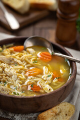 Bowl of chicken noodle soup with carrots on a napkin