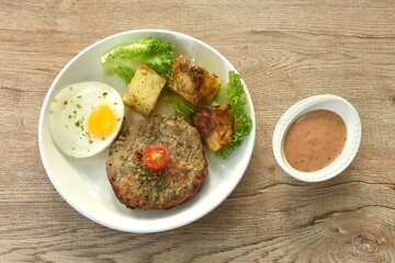 grilled black pepper pork collor steak and lettuce with tomato couple fried egg on plate dipping gravy sauce in cup