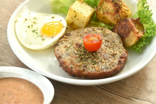 grilled black pepper pork collor steak and lettuce with tomato couple fried egg on plate dipping gravy sauce in cup