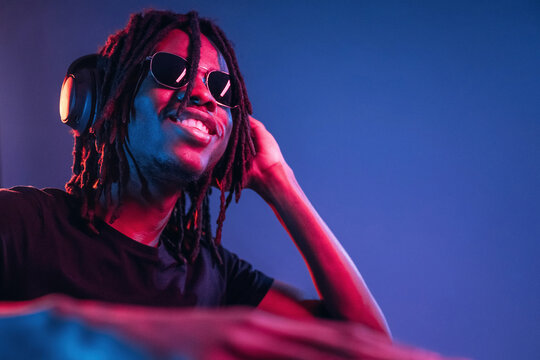 DJ in club. African American guy is studio with neon lighting