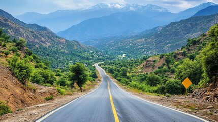 Naklejka premium Driving Through Mountain Valley with Winding Road and Snowy Mountain Peaks
