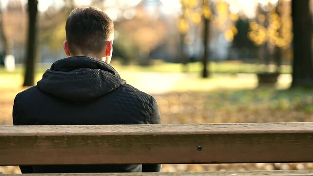 A person sitting alone on a park bench looking dejected