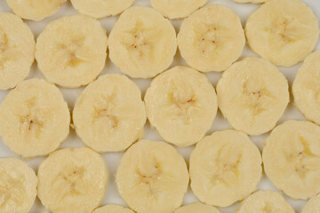 A close-up, top-down view of numerous banana slices arranged in a grid pattern