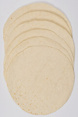 A close-up shot features a stack o flat, round tortillas, showcasing their texture and slightly varied tones