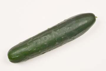 A top-down, angled shot of a whole, dark green cucumber against a plain, light background