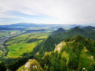 Stunning panoramic view of Pieniny mountains in Poland, with lush valleys, dense forests, and distant peaks under a cloudy sky.