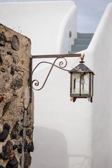Vertical photo of a broken Greek traditional old lantern with black metal ornaments in Pyrgos Kallistis, Santorini, Greece. A perfect day trip from Fira to explore the islands mainland hidden gem