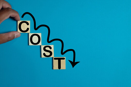 A hand arranging wooden blocks to spell 'COST' in a decreasing order with an arrow pointing downward. A perfect image for cost reduction,financial planning, and business management.