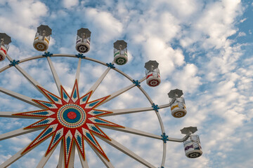 Ferris wheel with empty gondolas against blue sky with white clouds at the amusement park shot on a sunny day, Sunset Park in La Libertad tourist beach town, El Salvador.