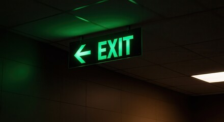 Green Exit Sign with Arrow Glowing in a Dark Hallway