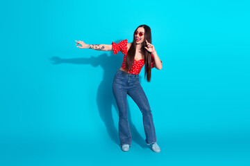 Young stylish woman in vibrant outfit posing against a bright blue background depicting happiness