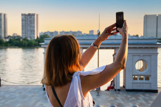 Woman Taking a Selfie at Sunset by the River.