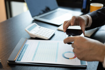 A man in a suit is holding a stack of papers and a pen. He is likely working on a project or preparing for a meeting. Concept of professionalism and focus, as the man is fully engaged in his task

