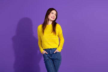 Smiling young woman in yellow sweater posing against purple background exudes cheerful energy and stylish casual fashion