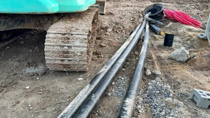 The construction site is filled with various machinery, pipes, and gravel, all prepared for an upcoming project