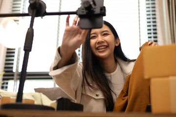 
A woman is holding two boxes and smiling. She is sitting in front of a laptop. The boxes are brown and appear to be gifts. The woman seems happy and excited about the boxes
