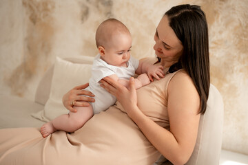 a mother holds a newborn baby in her arms, a mother gently hugs and kisses a small child, maternal love and care, a mom and a baby
