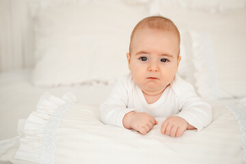 newborn baby on a white bed at home, a small child, a boy in white clothes, a healthy baby