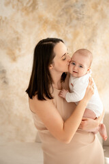 a mother holds a newborn baby in her arms, a mother gently hugs and kisses a small child, maternal love and care, a mom and a baby