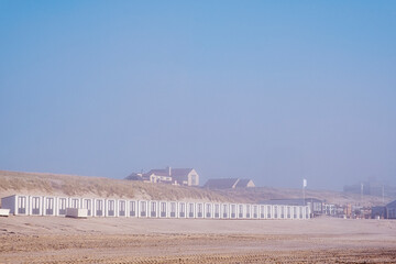 A row of beach huts on the Dutch North Sea coast near Bergen aan Zee in foggy weather